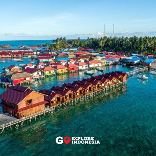 Penginapan atas air atau cottage up water di Pulau Derawan dengan pemandangan laut biru.